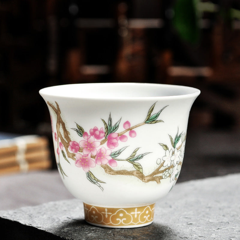 Dehua porcelain tea cup with pink and white blossoms on brown branches and slender green leaves