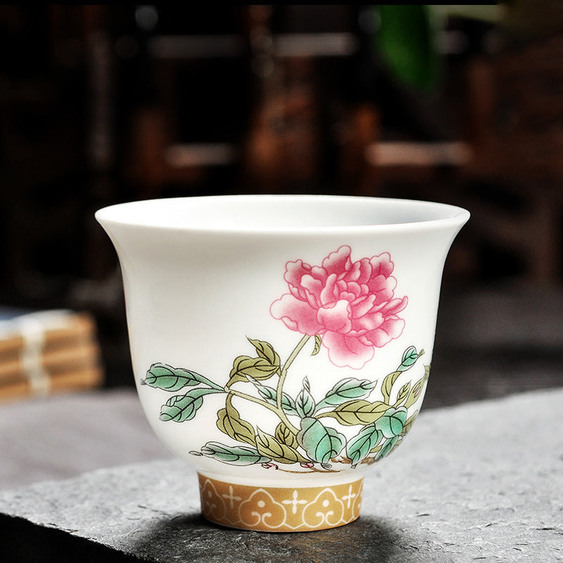 Dehua porcelain tea cup with a single large pink bloom above clustered green leaves