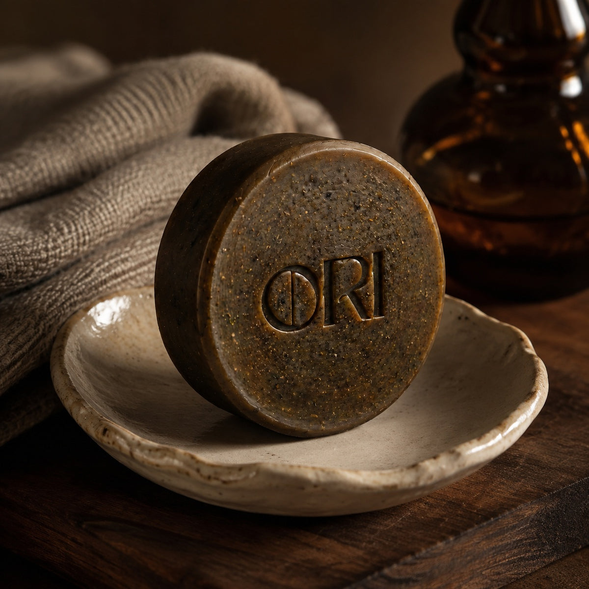Dong herbal facial soap bar: Standing in a ceramic dish beside a bottle
