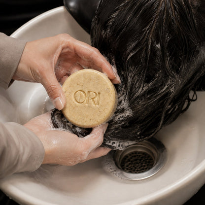 Ginger and astragalus shampoo bar: Shown washing wet hair over a basin