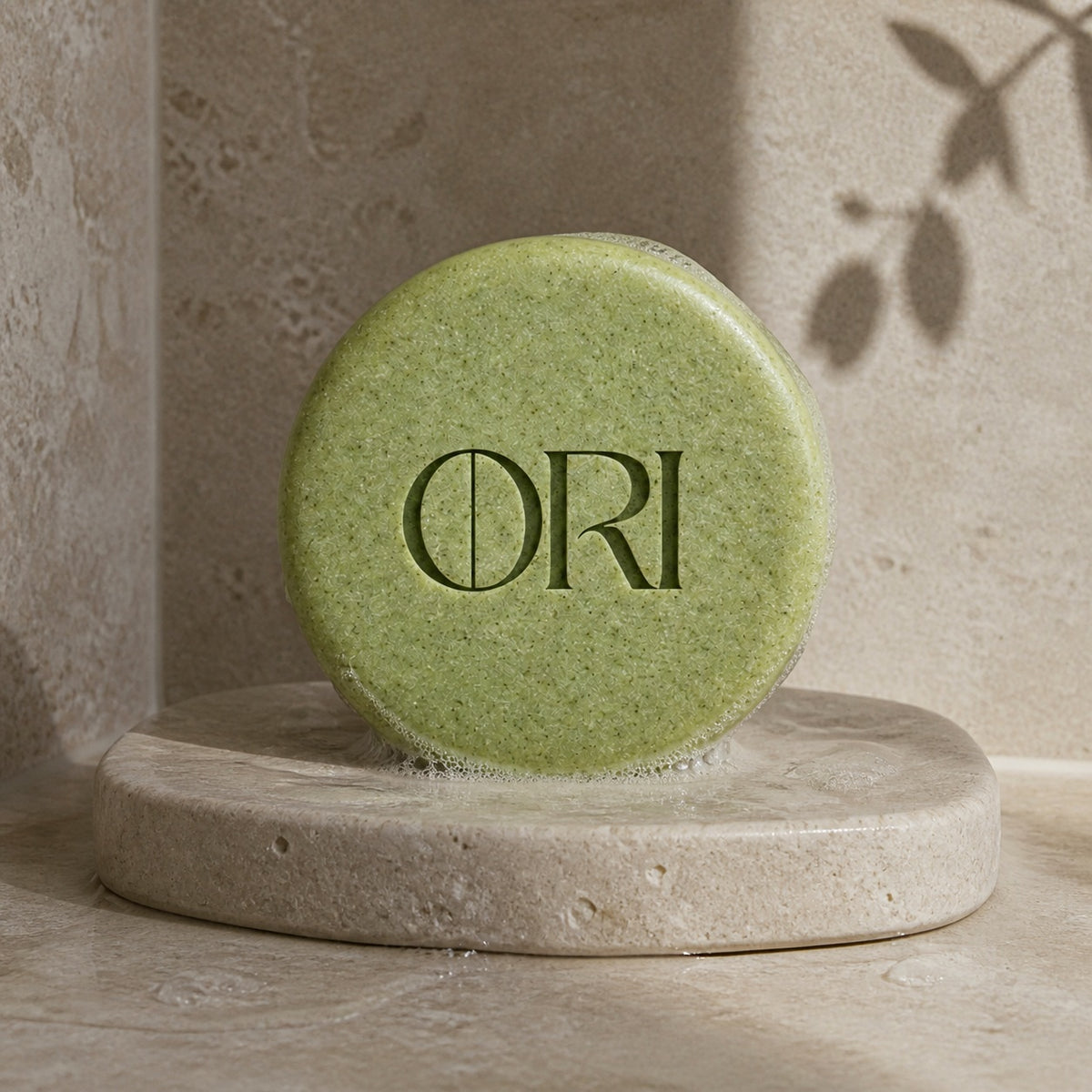 Matcha green tea soap bar: Green round bar on a sunlit stone dish