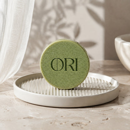 Matcha green tea soap bar: Standing on a white ridged soap dish