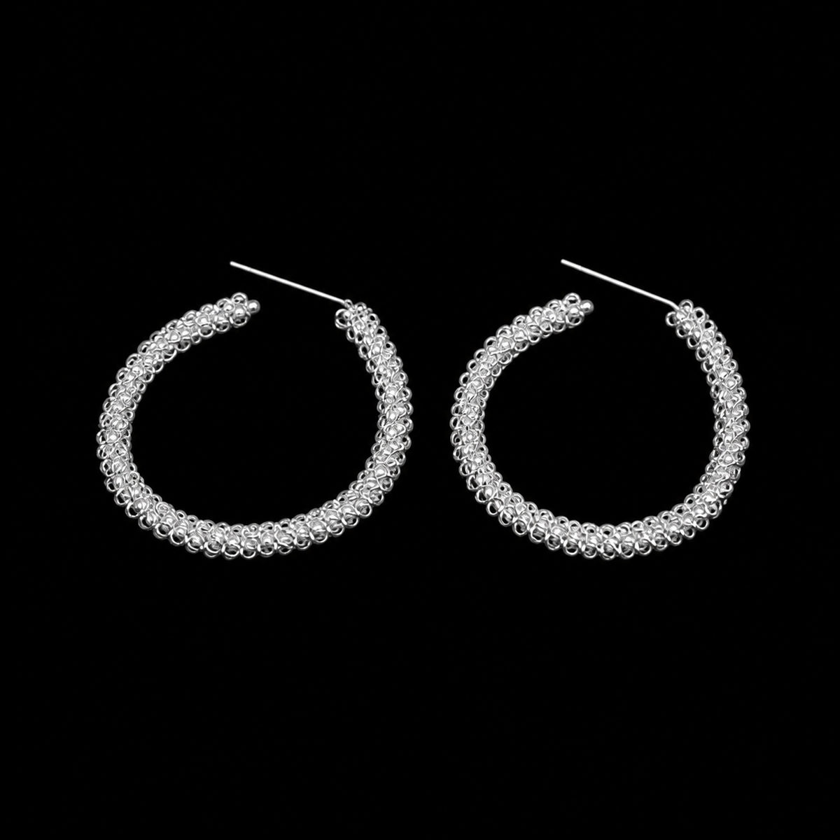Miao silver hoop earrings: Front view of the hoop pair on black