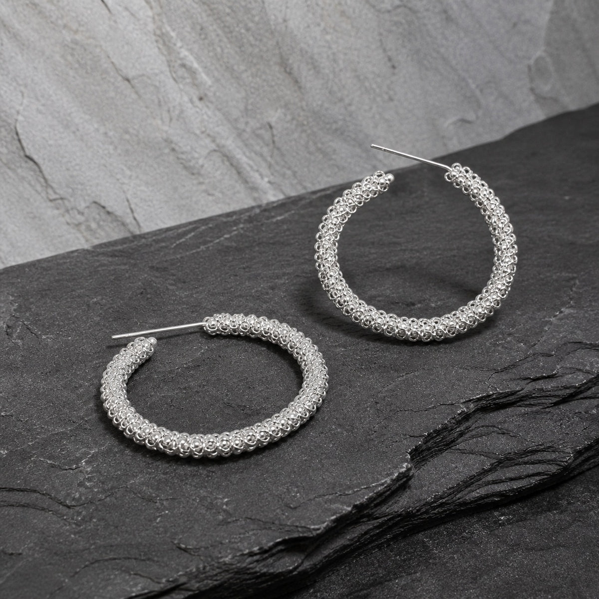 Miao silver hoop earrings: Pair of hoops on gray stone