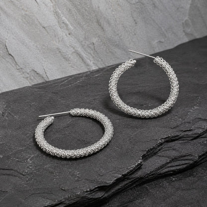 Miao silver hoop earrings: Pair of hoops on gray stone