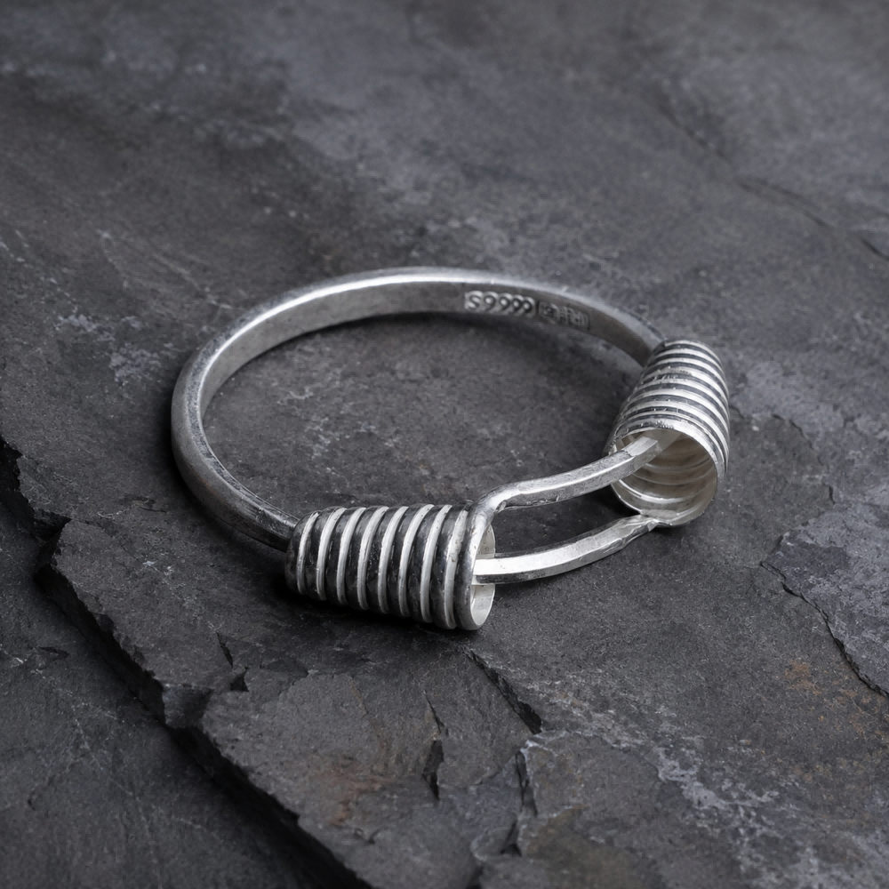 Miao silver spiral bracelet: Angled view of coiled ends on slate