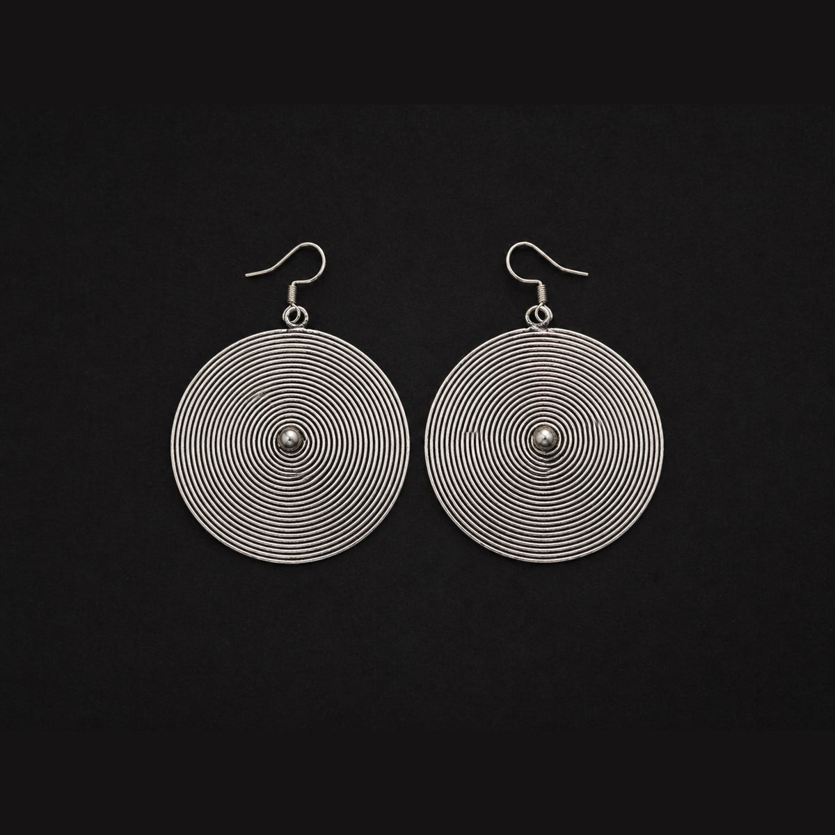 Miao silver spiral disc earrings: Pair of round spiral discs on a dark background