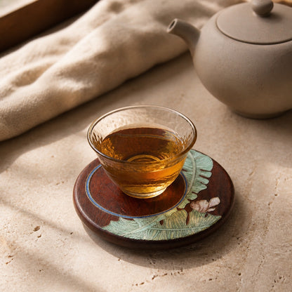 Round red sandalwood cloisonne coaster: Green botanical design beneath a glass teacup