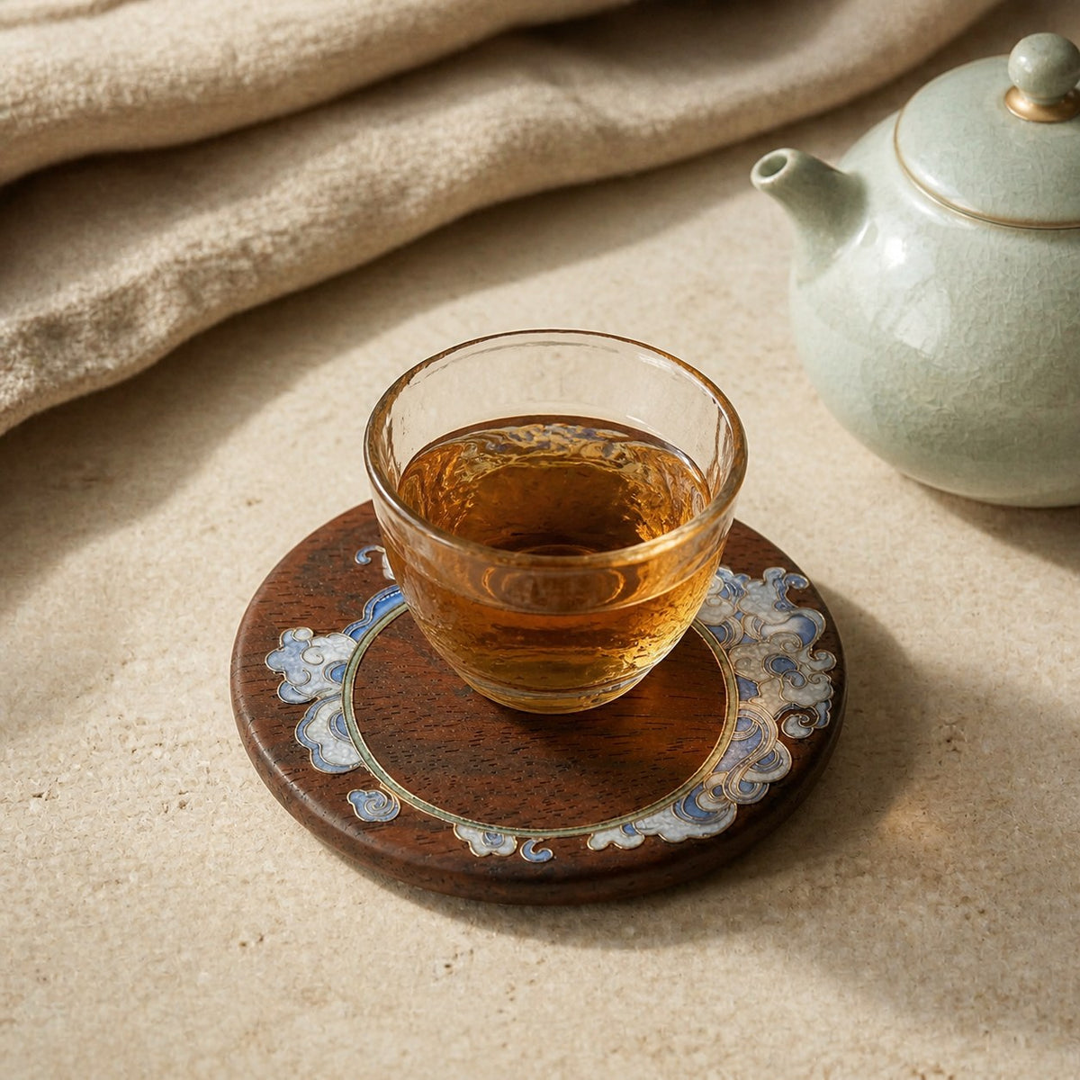Round red sandalwood cloisonne coaster: Pale blue floral design beneath a glass teacup