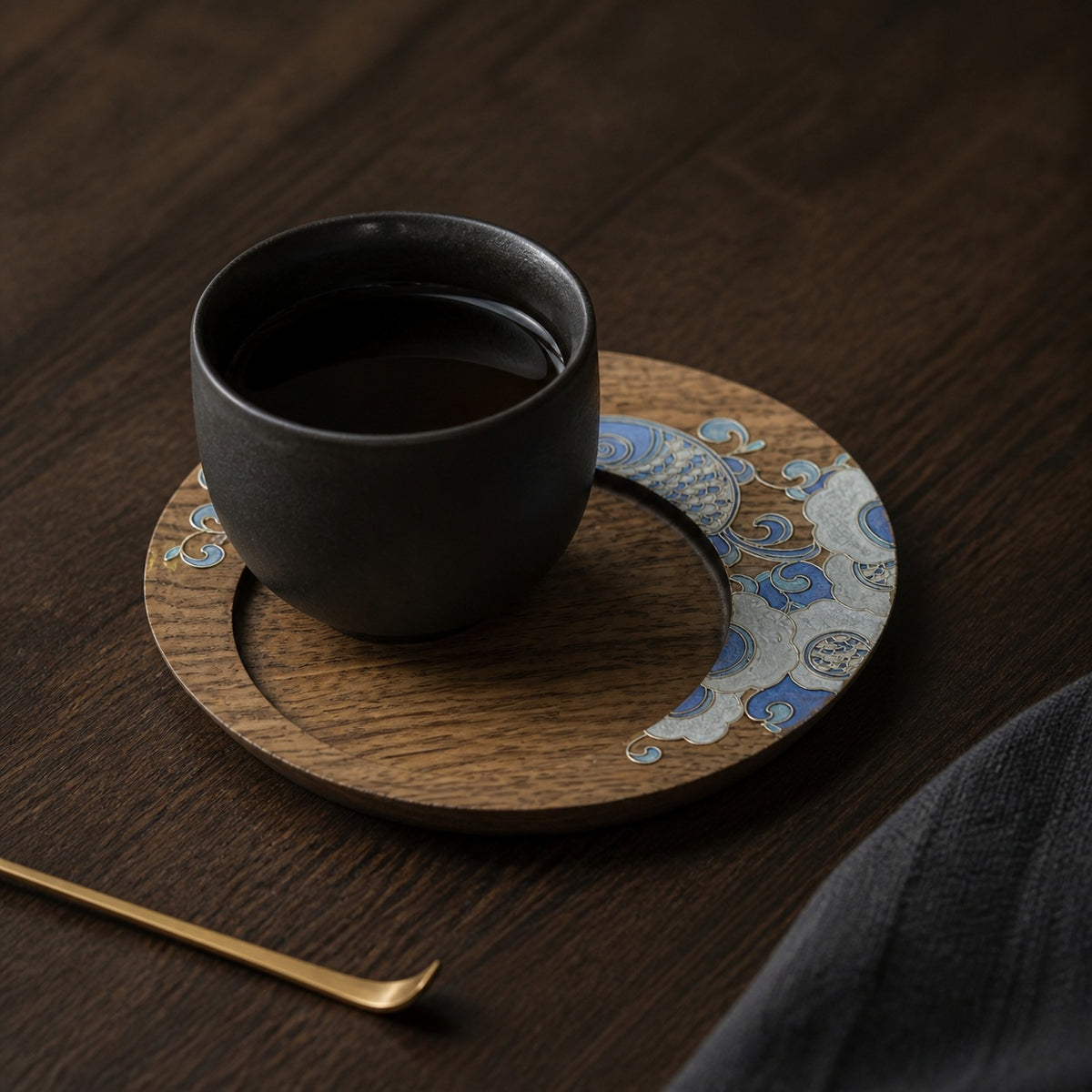 Round walnut cloisonne coaster: Pale blue floral design beneath a black cup