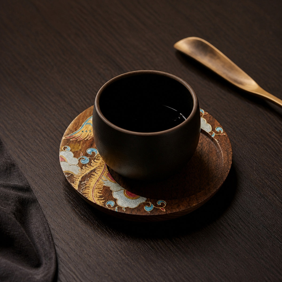 Round walnut cloisonne coaster: Yellow floral design beneath a black cup