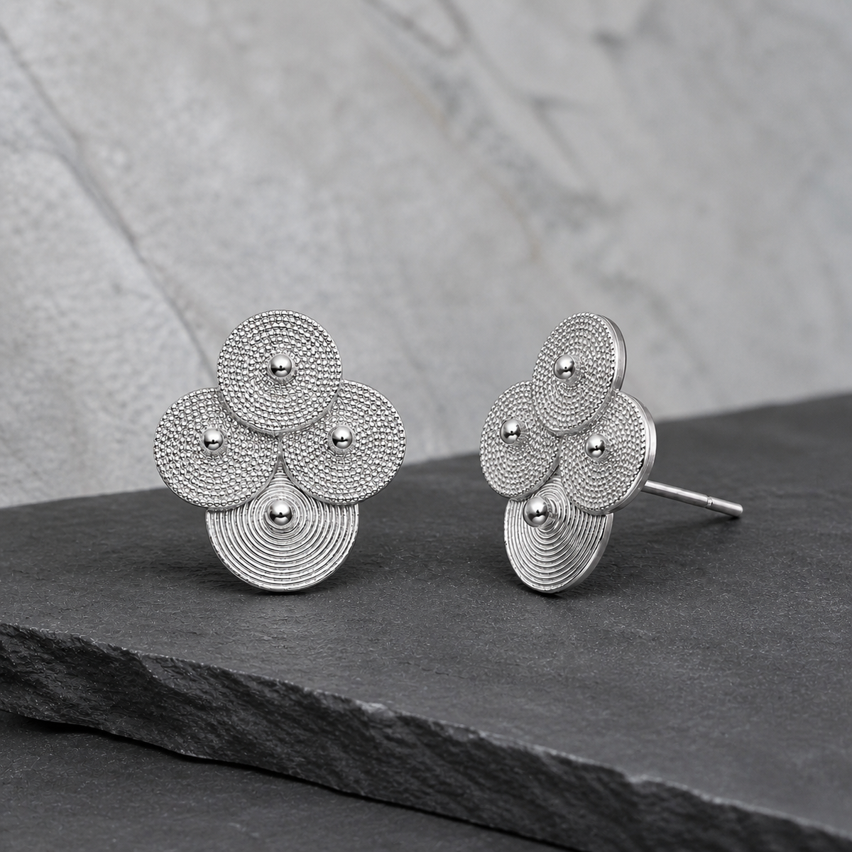 Silver spiral-disc cluster studs: Front and side views of cluster studs on gray stone