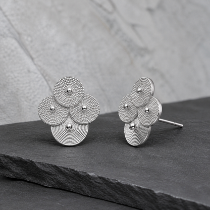 Silver spiral-disc cluster studs: Front and side views of cluster studs on gray stone