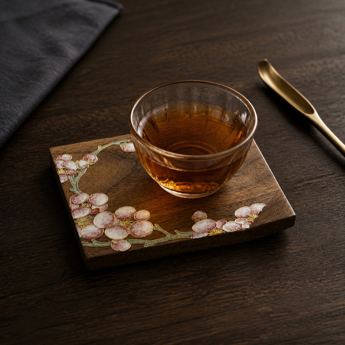 Square walnut cloisonne coaster: Pale blossom design beneath a glass teacup