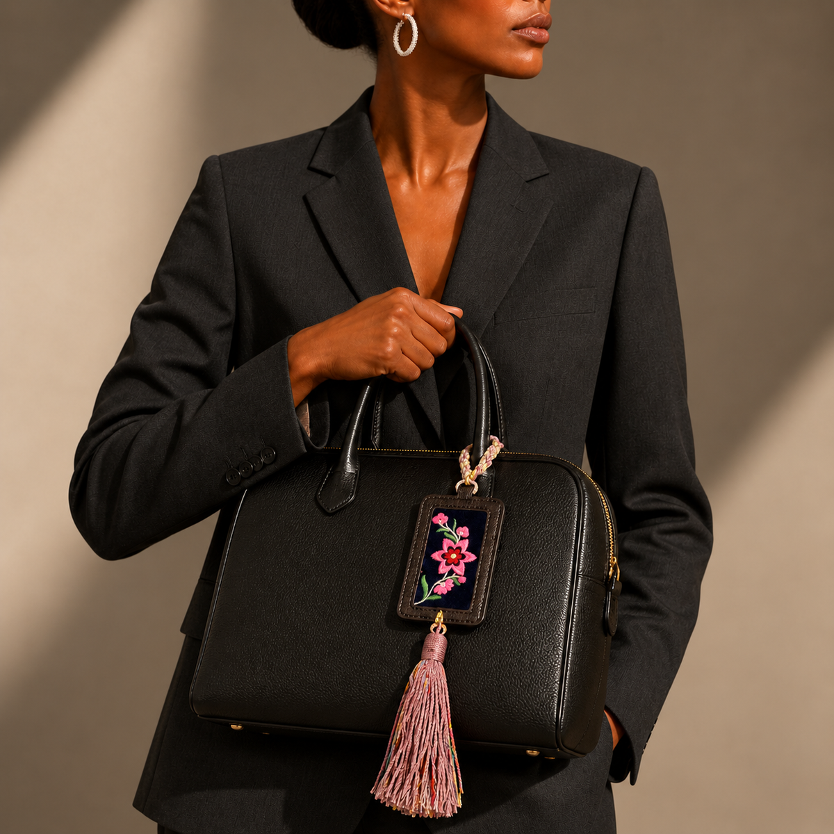 Xixiu embroidered luggage tag: Pink floral tag attached to a black handbag carried by a model