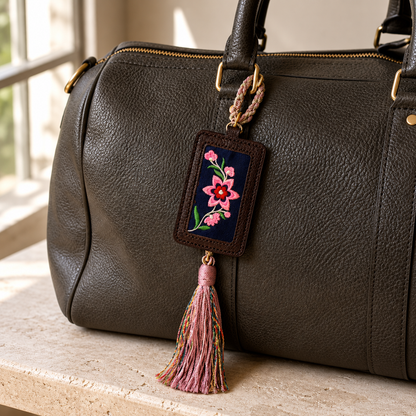 Xixiu embroidered luggage tag: Pink floral tag attached to a dark leather bag