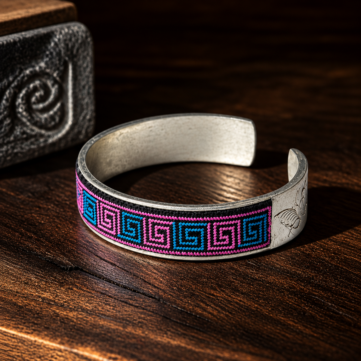 Xixiu embroidered silver cuff: Pink and blue cuff on a wooden surface